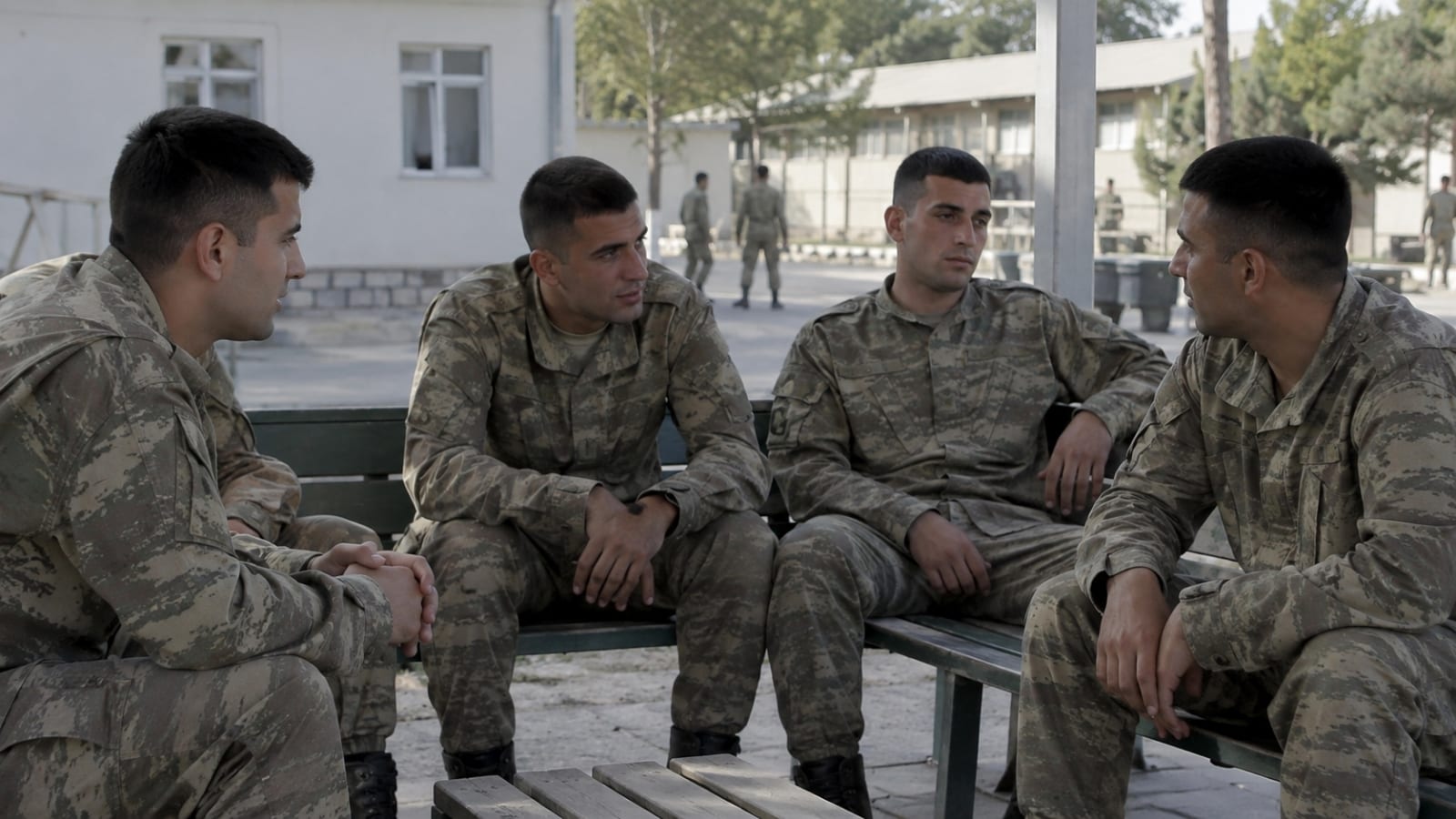 Kışla yerleşkesindeki ortak dinlenme alanında birlikte oturup sohbet eden dört Türk askerî personel