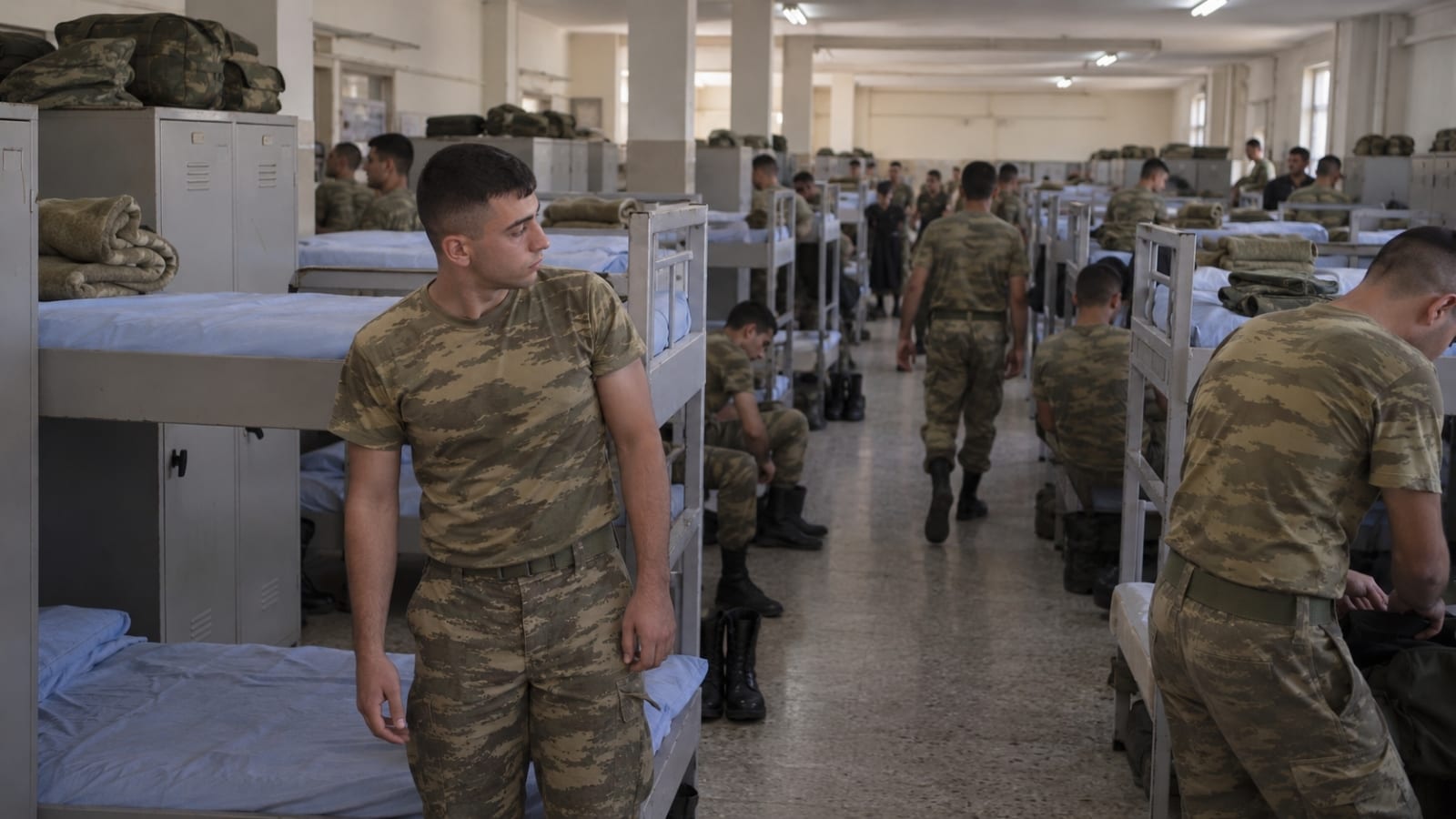 Çok sayıda ranza ve ortak dolabın bulunduğu kalabalık asker koğuşunda kendine alan bulmaya çalışan Türk askerî personel